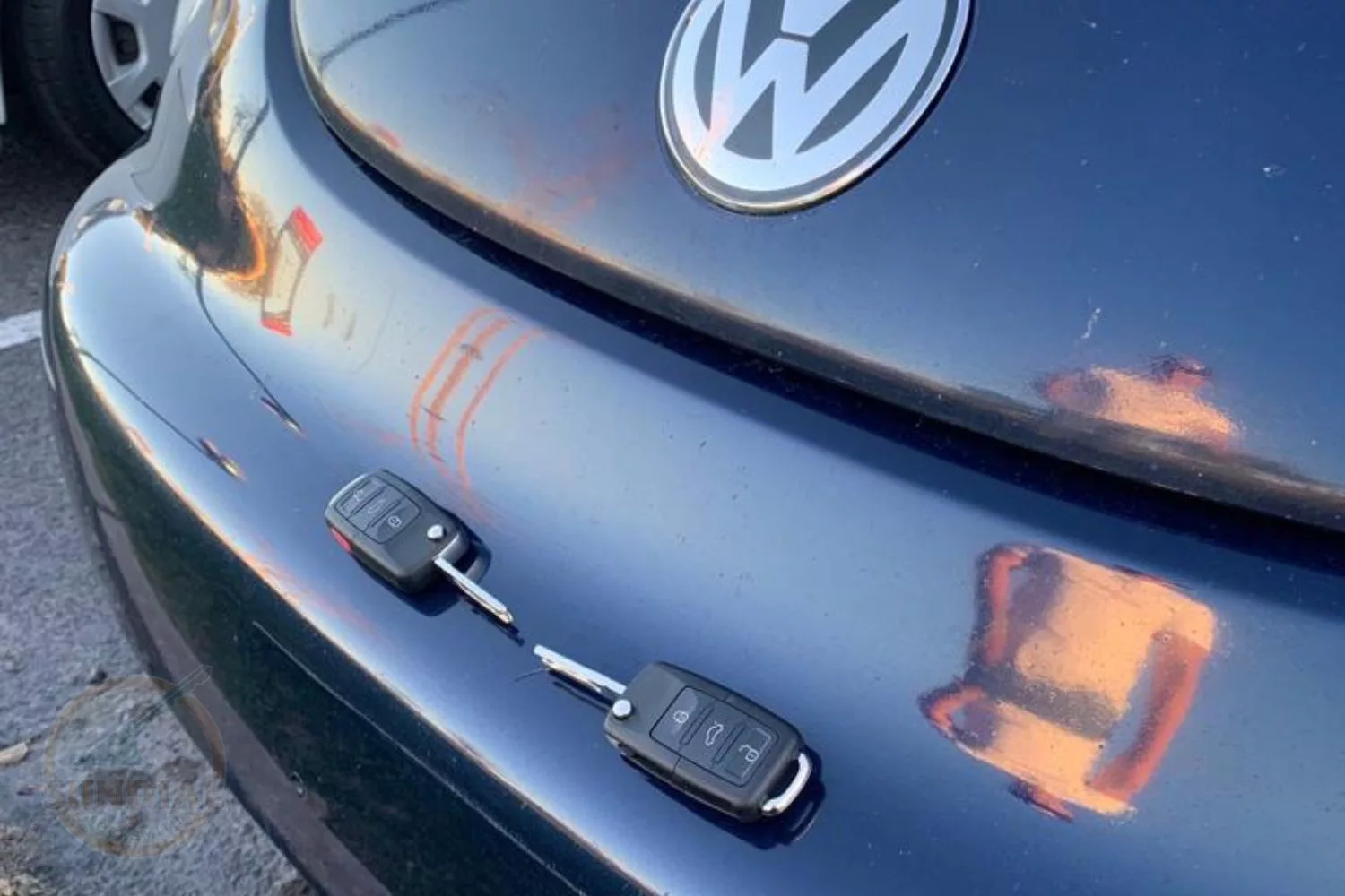 Close-up of a Volkswagen car emblem with two car keys dangling on its surface.