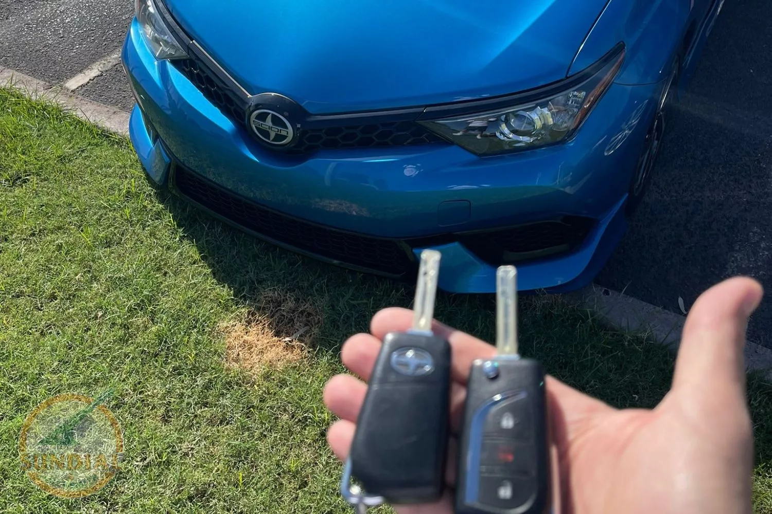 Hand holding car keys with blue Scion car background