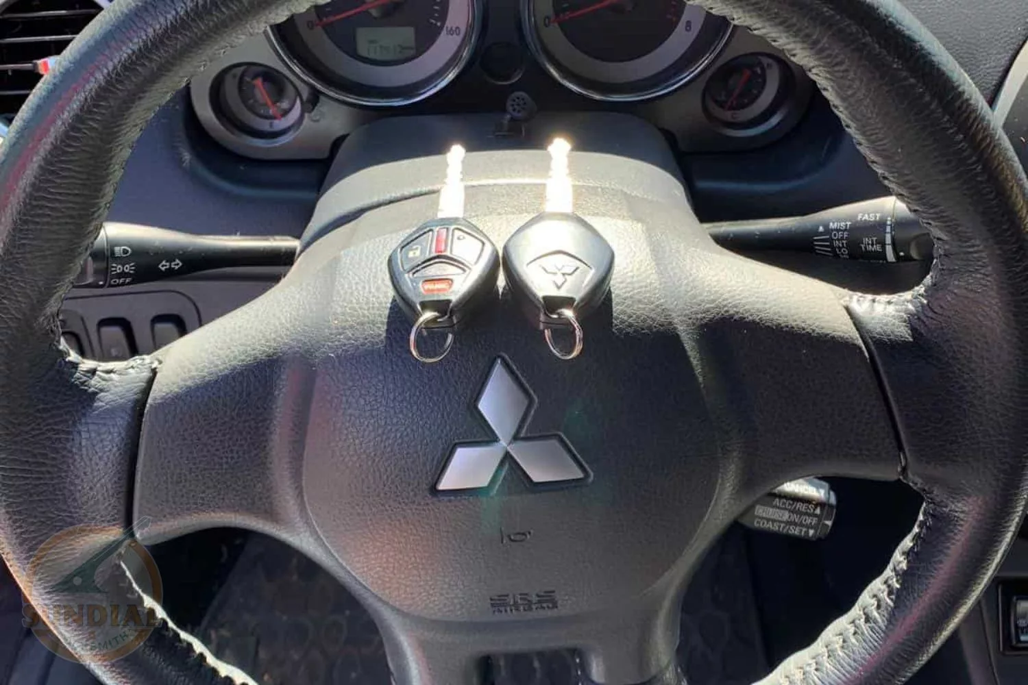 Mitsubishi car keys on a steering wheel