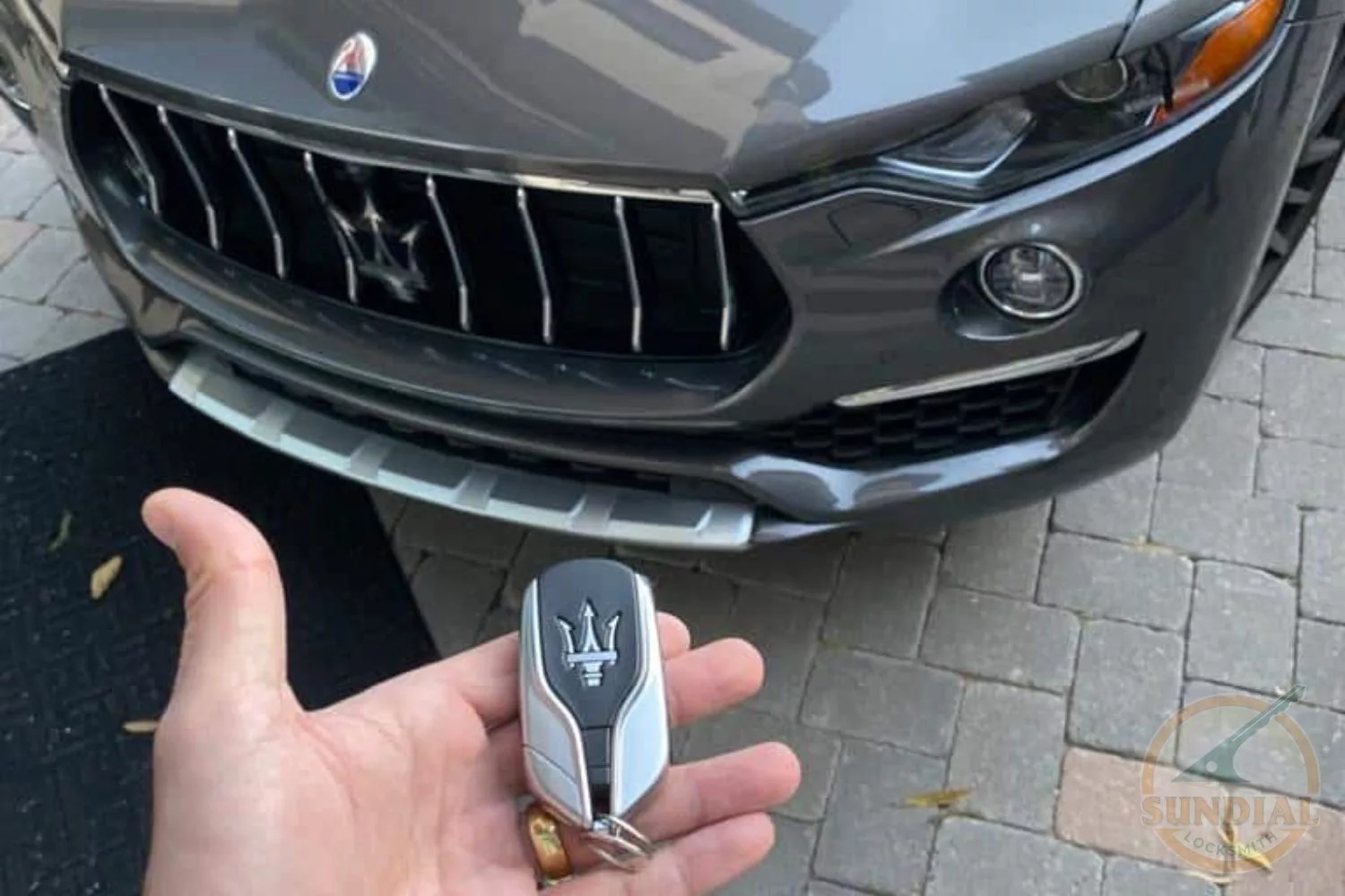 Hand holding a Maserati car key fob.