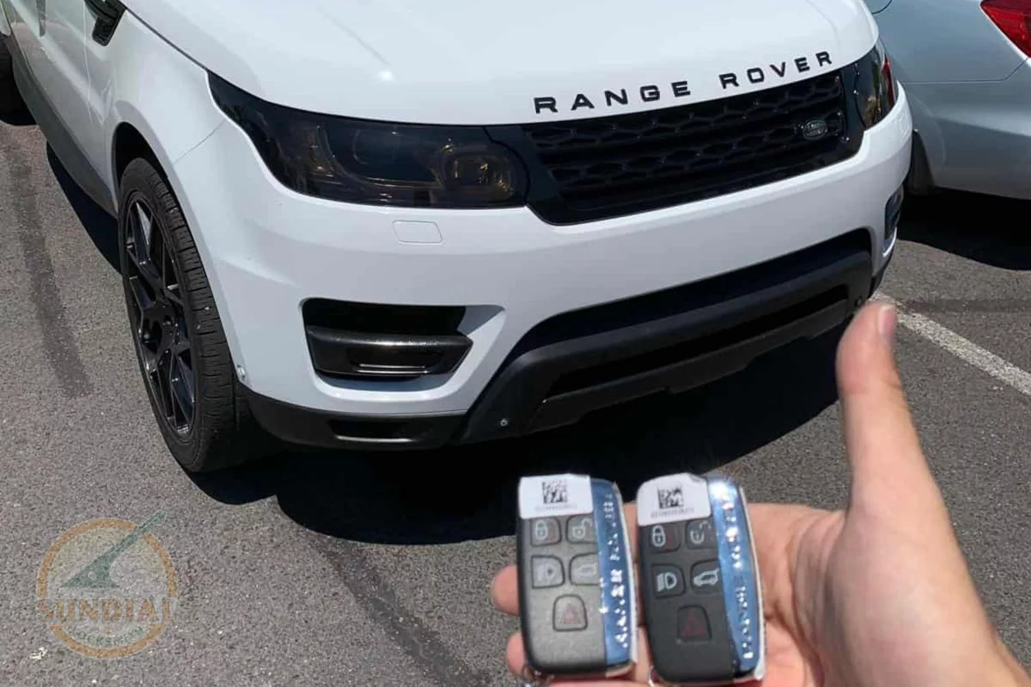 Hand holding keys to white Range Rover.