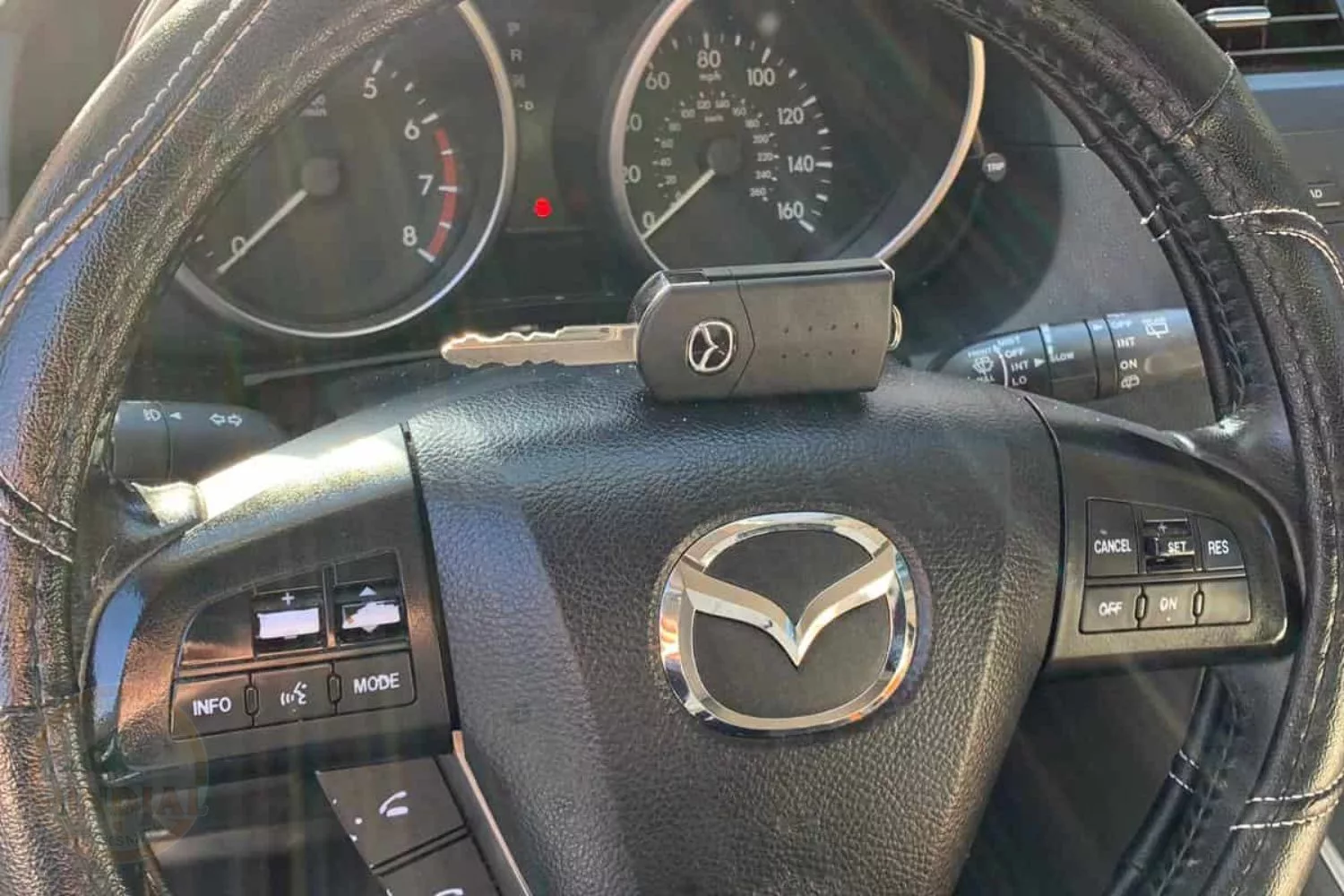 Mazda car steering wheel and dashboard view.