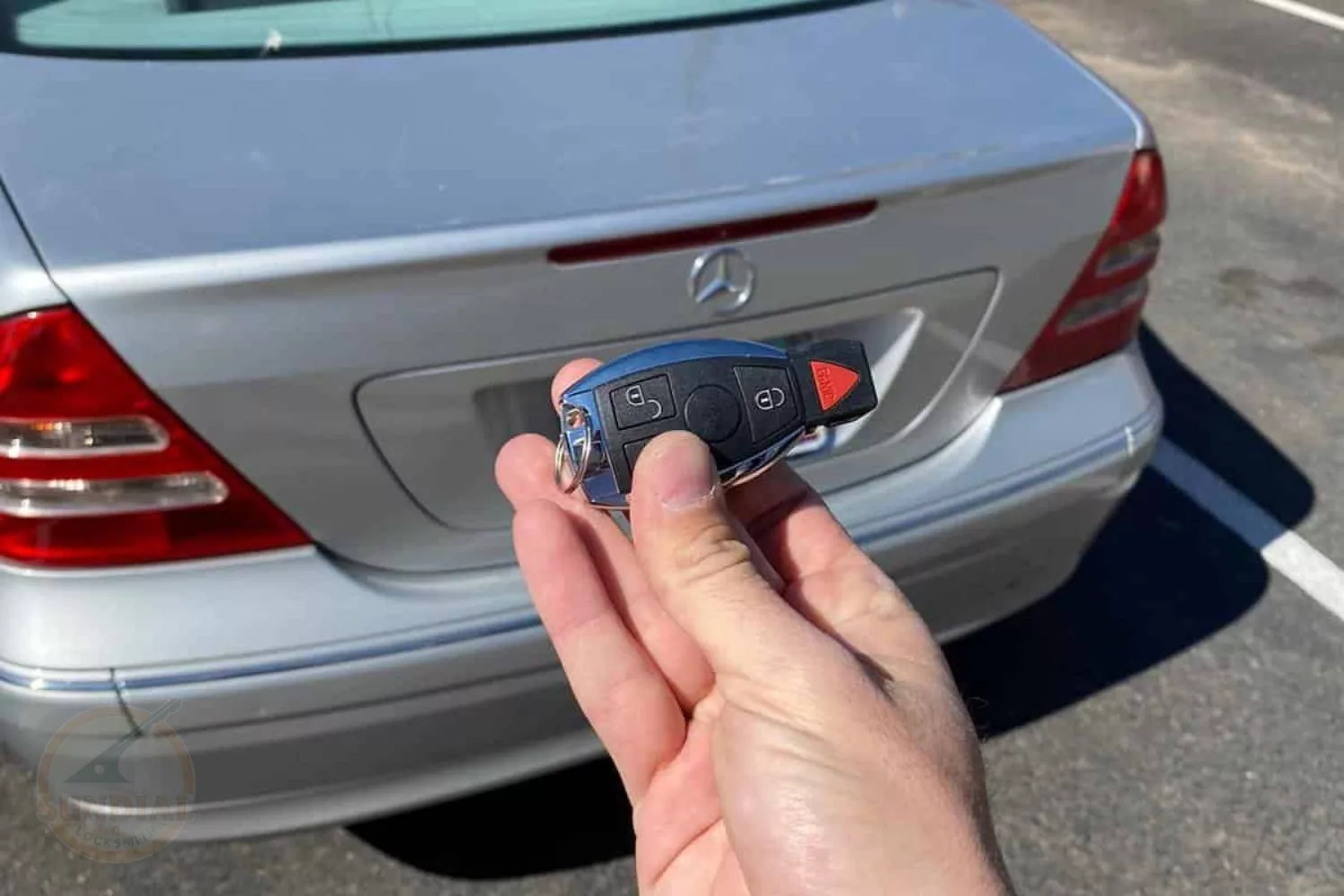 Hand holding a car key fob near vehicle.