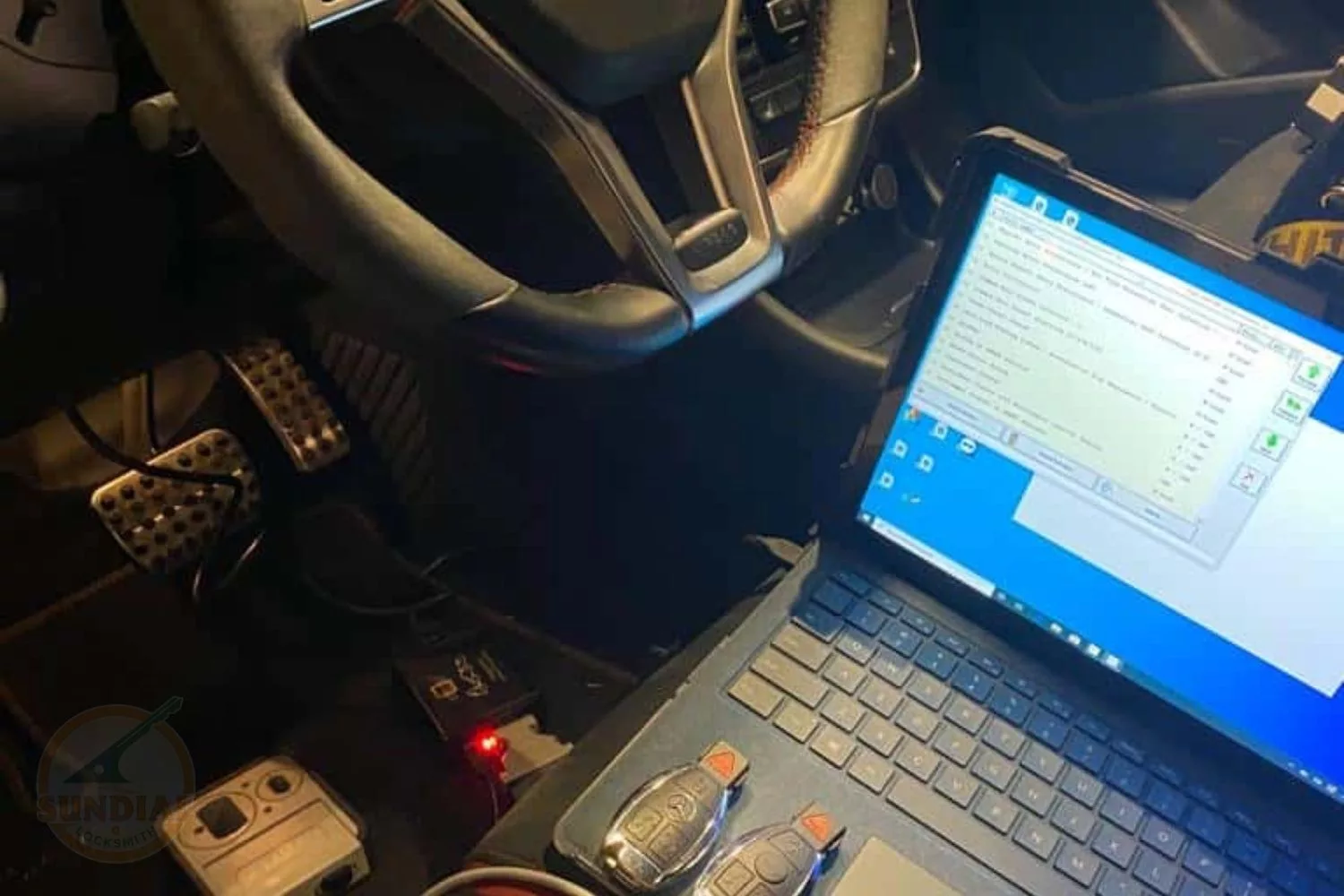 Car diagnostics with laptop and tools inside vehicle.