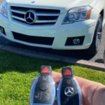 Holding car keys in front of a white Mercedes-Benz.
