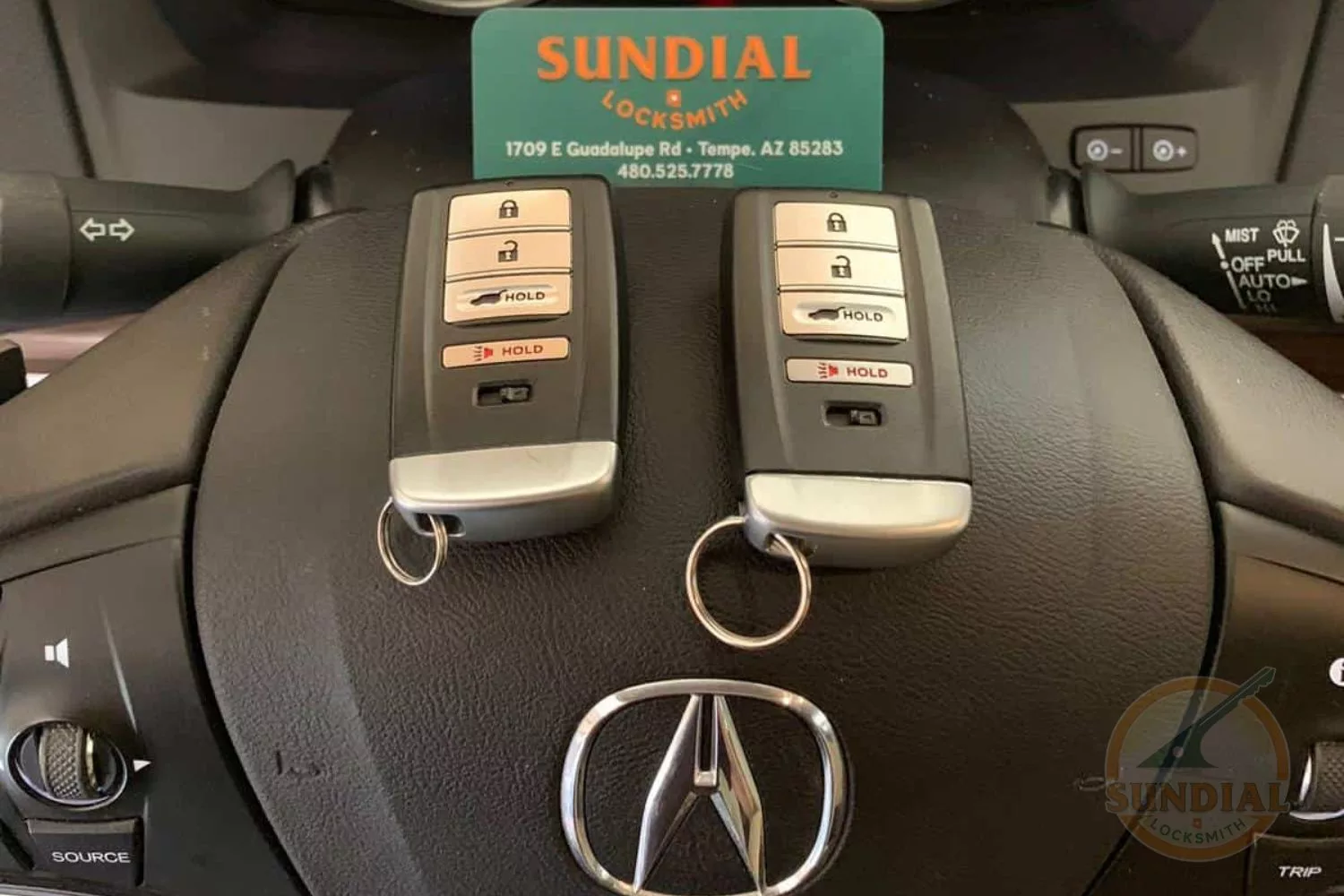 Car keys on steering wheel with locksmith business card.