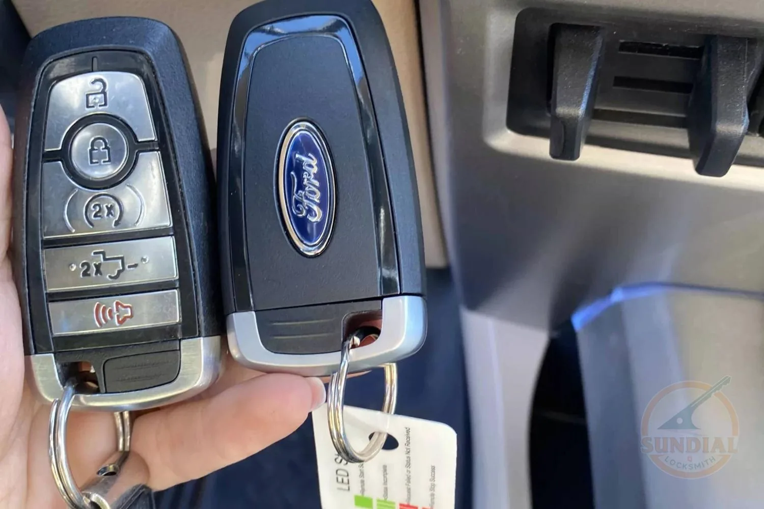 Hand holding Ford car keys with remote controls.