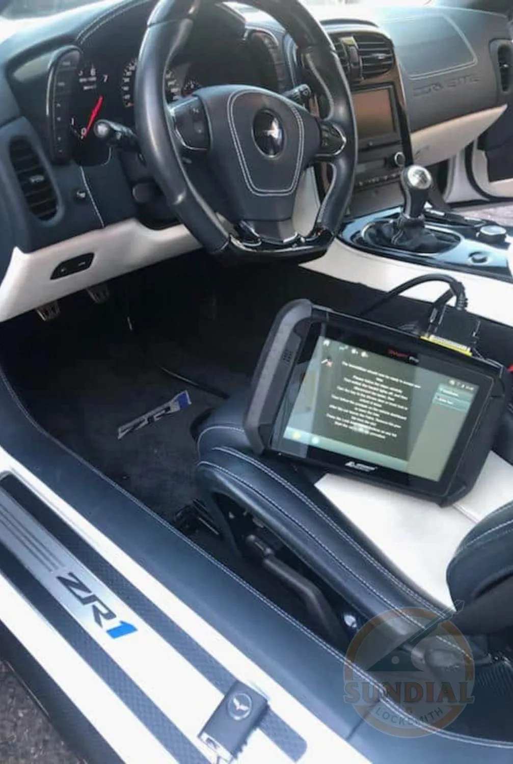 Automotive diagnostic tablet on a sportscar's seat, displaying data with the car's interior and steering wheel in view