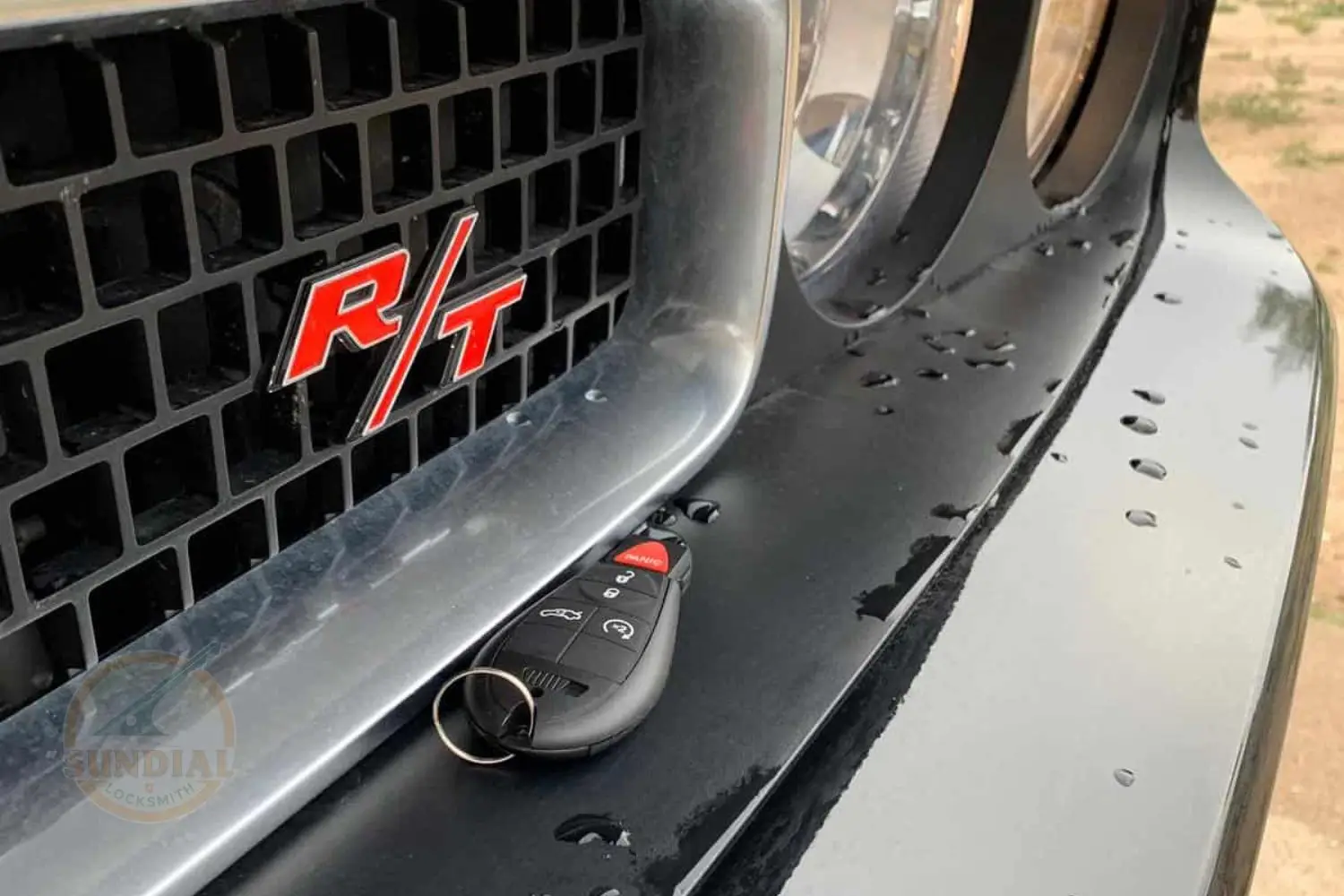 Dodge logo with R/T emblem on a car's grille and a key fob resting on the hood.