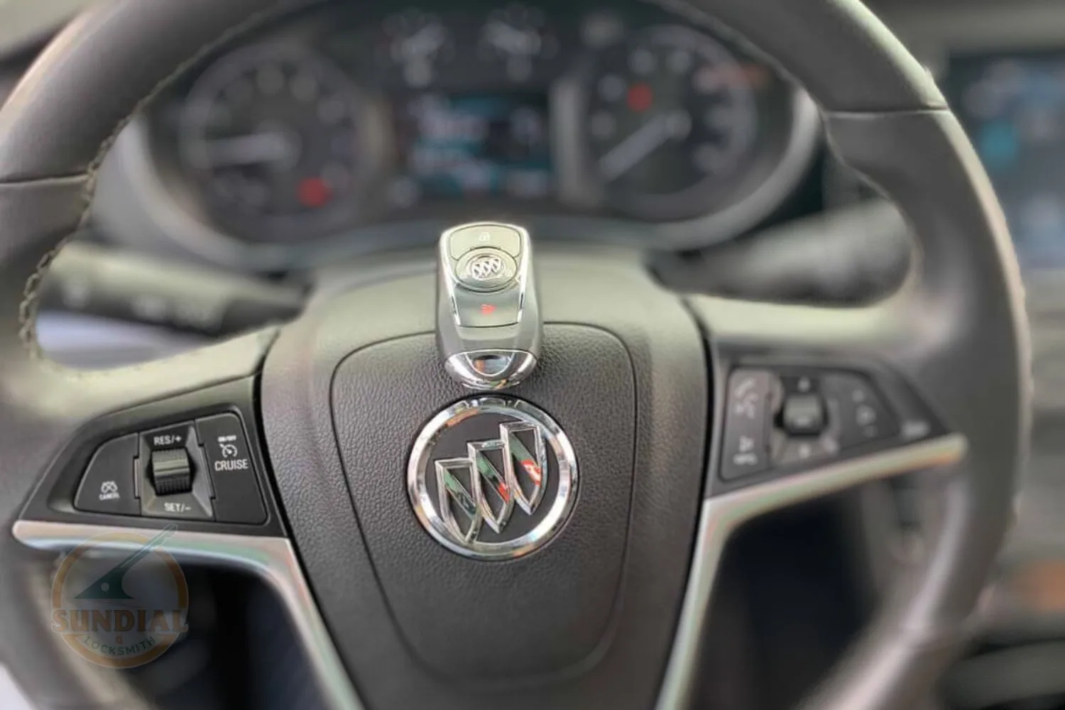 A Buick car key fob placed on the steering wheel emblem inside the vehicle, highlighting professional locksmith services.