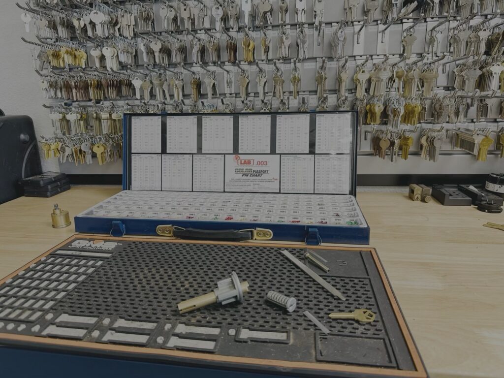 Can You Rekey Your Own Locks? What DIY Gets Right and Wrong A locksmith workbench with a blue key blank organizer case, lock cylinder tools, and brass keys in front of a wall display filled with hundreds of key blanks.