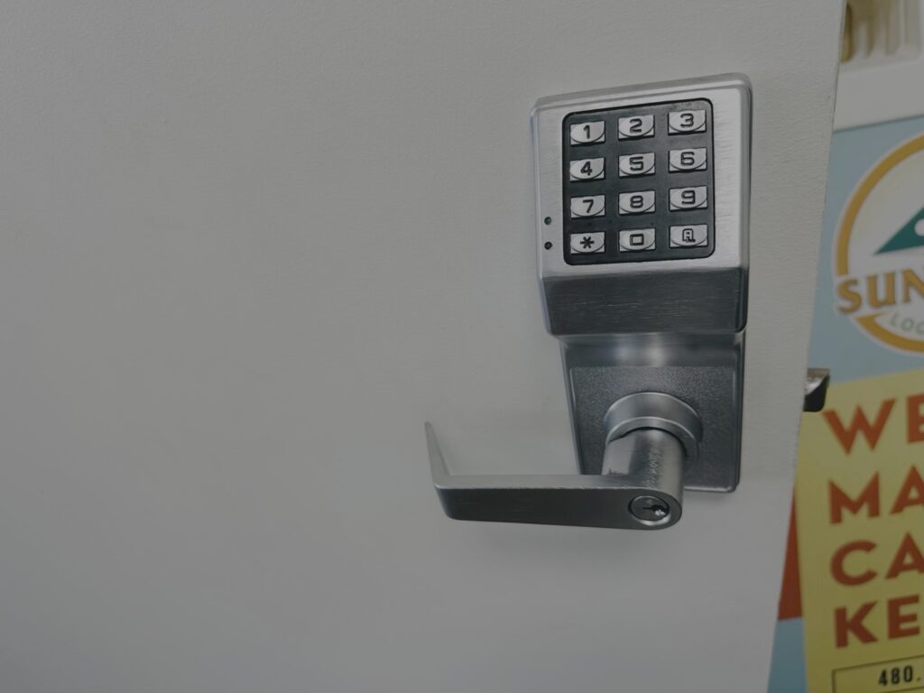 A stainless steel electronic keypad lock with lever handle mounted on a white commercial door.
