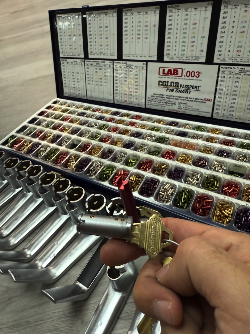 A locksmith technician performing a rekeying commercial building service on a cylinder lock at a Phoenix office building entry door in natural daylight