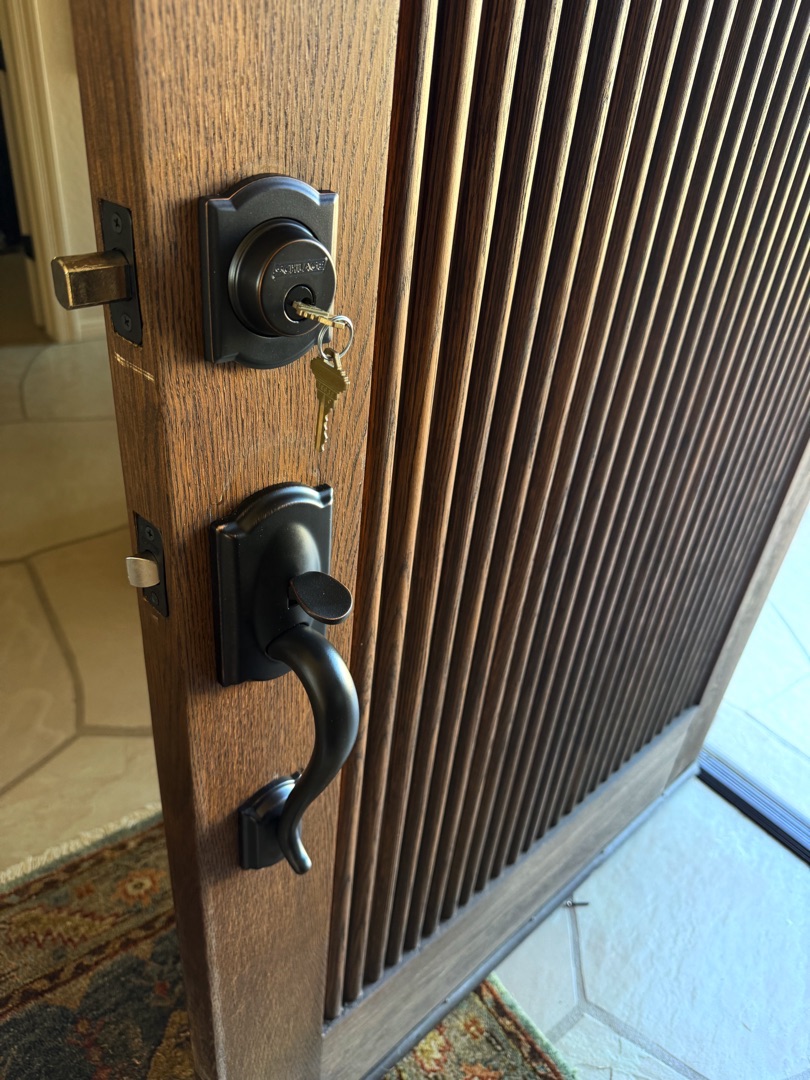 Grade 1 Deadbolt Installation: What It Is and Who Actually Needs One A locksmith performing grade 1 deadbolt installation on a solid wood front door in warm afternoon sunlight in