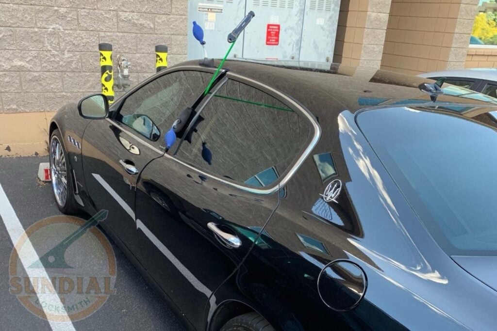 Anti-Kick Door Reinforcement: The Upgrade That Actually Stops Kick-In Burglaries A locksmith working on the door of a black Maserati sedan in a parking lot using specialized tools to gain entry.