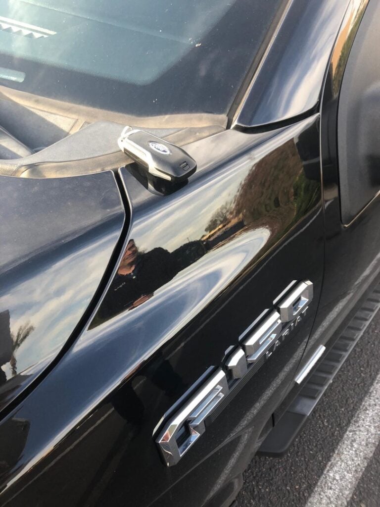 Do Burglars Actually Pick Locks? The Truth Might Surprise You A black key fob resting on the shiny hood of a black pickup truck in a parking lot.