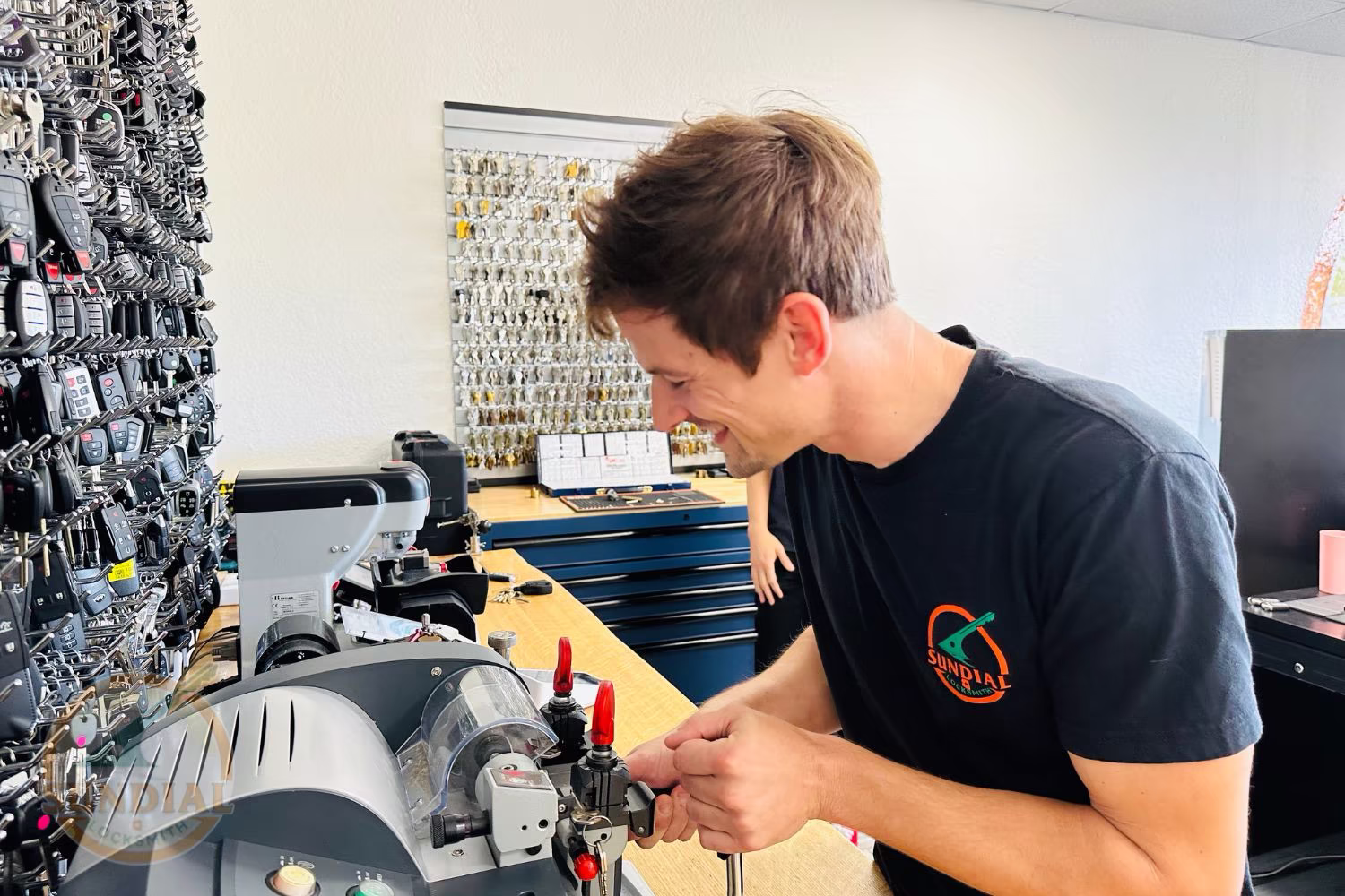 A professional locksmith using key programming equipment beside a white Ford Transit work van — the kind of locksmith for work van response that gets contractors back on the road fast.